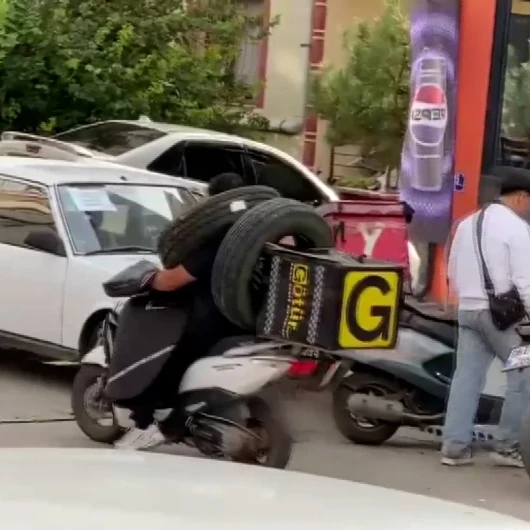 Kuryenin lastik taşıma yöntemi şaşırttı: Boynuna astı