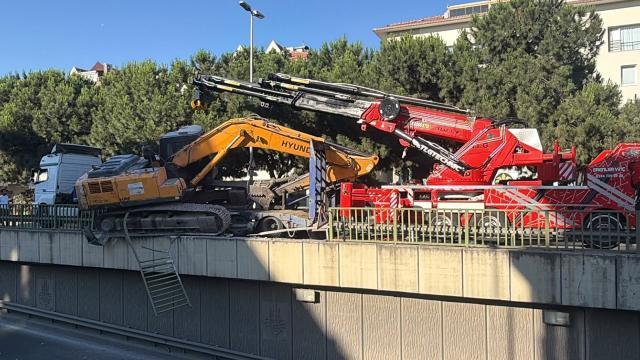 Tırın üzerinden düşen ekskavatör alt geçit korkuluklarında asılı kaldı